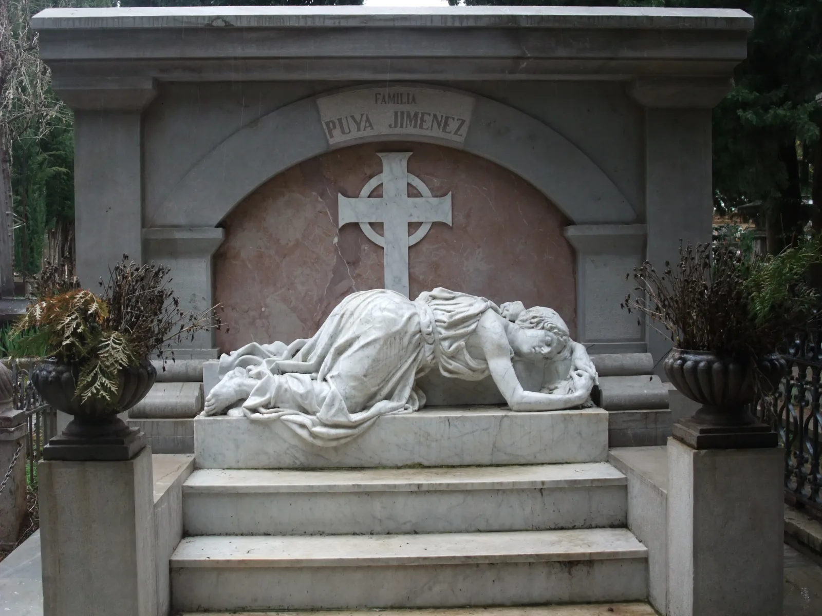 Panteón familiar en el cementerio de San José de Granada, con una escultura de mármol de una mujer tendida ante una cruz y macetas a los lados